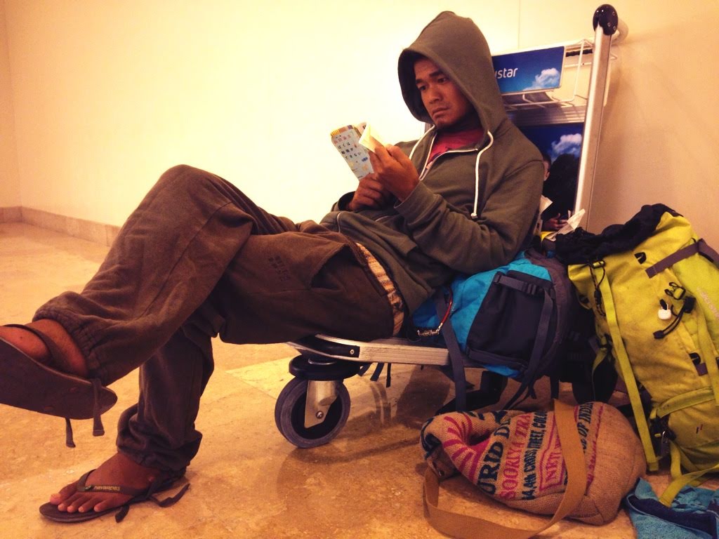 空港のカートに腰かけて本を読む男